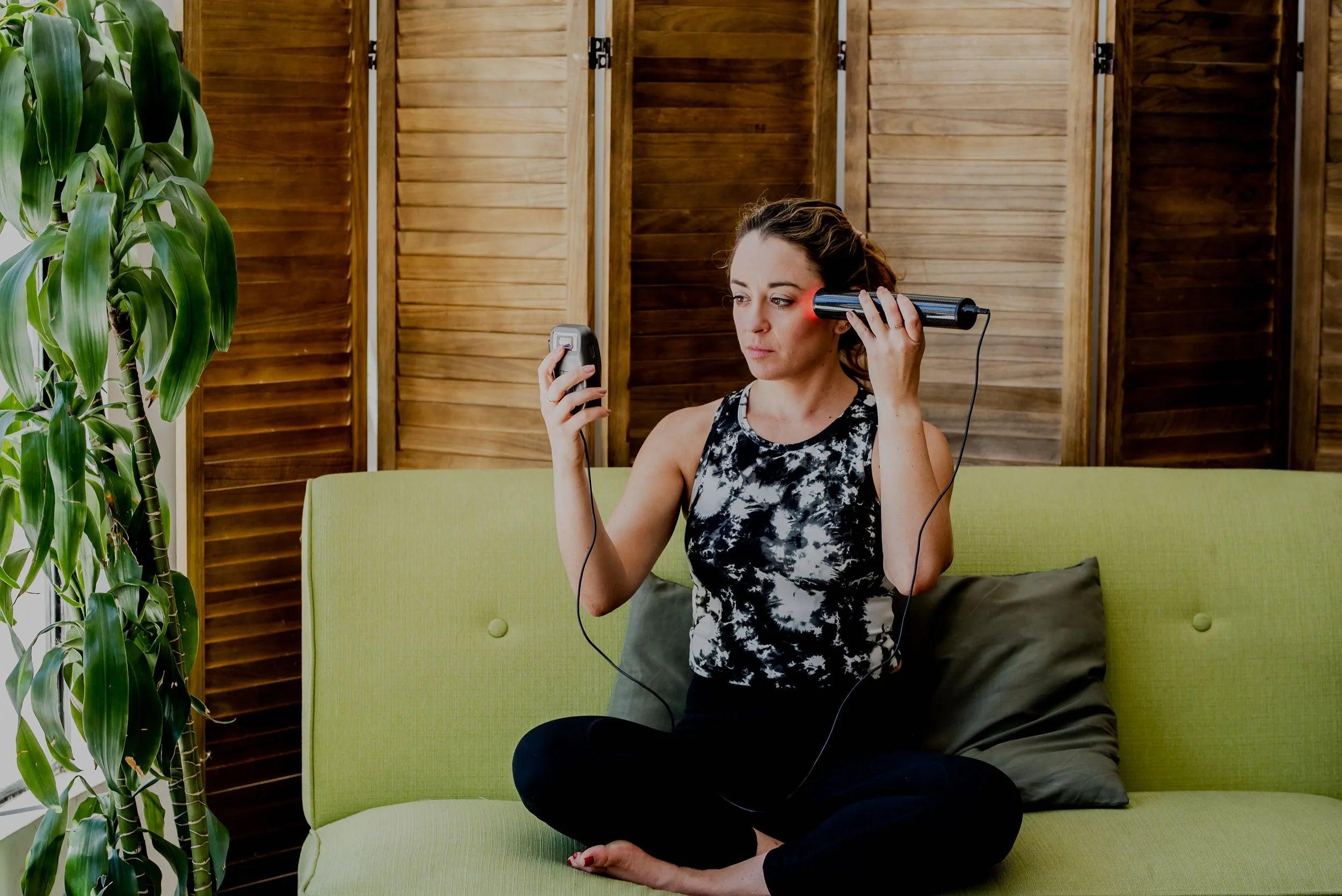 photo of a woman sitting crossed legged on a couch using the biotransducer pro on her left temple