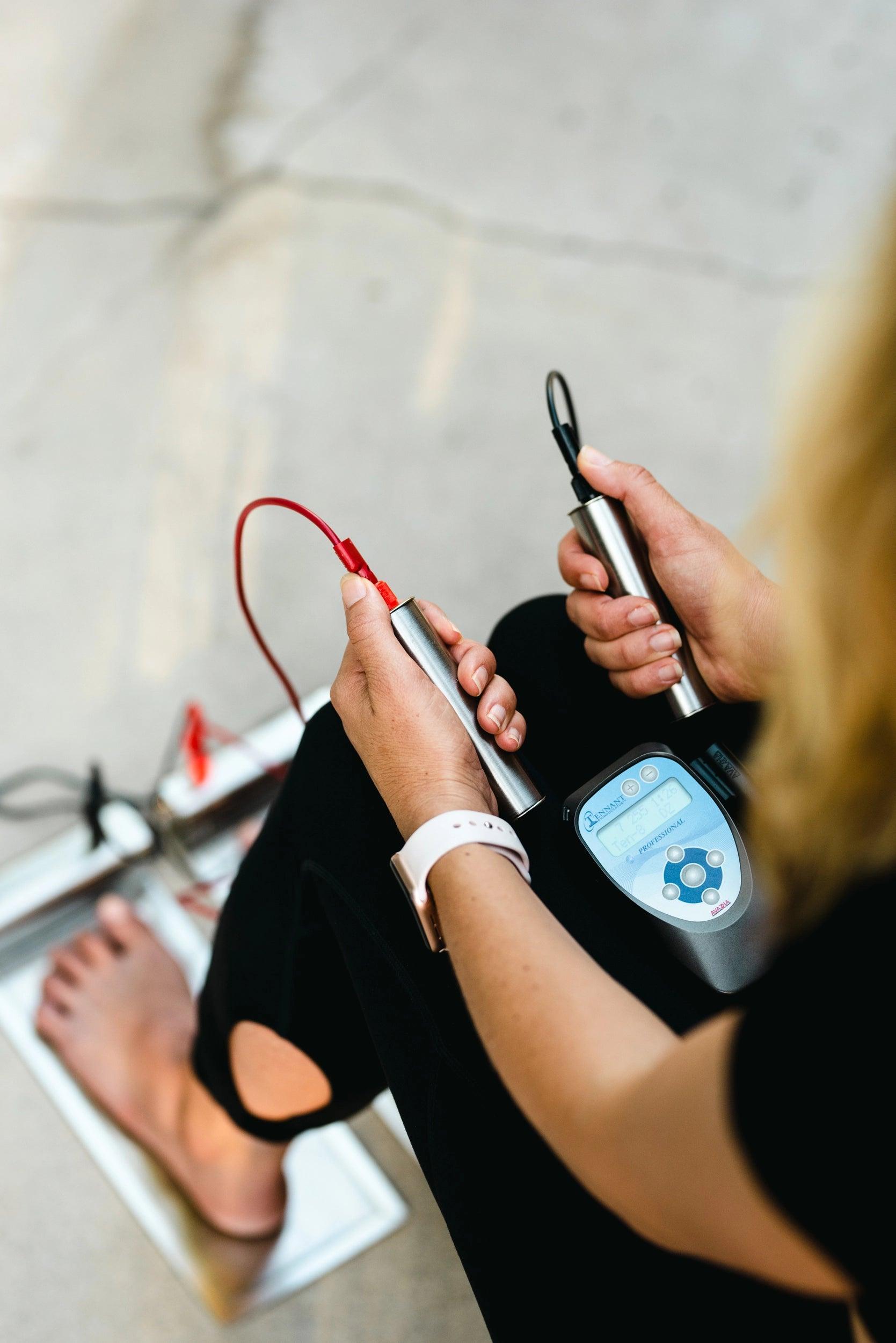 photo of a woman using the foot plates, hand grips with the biomodulator pro 