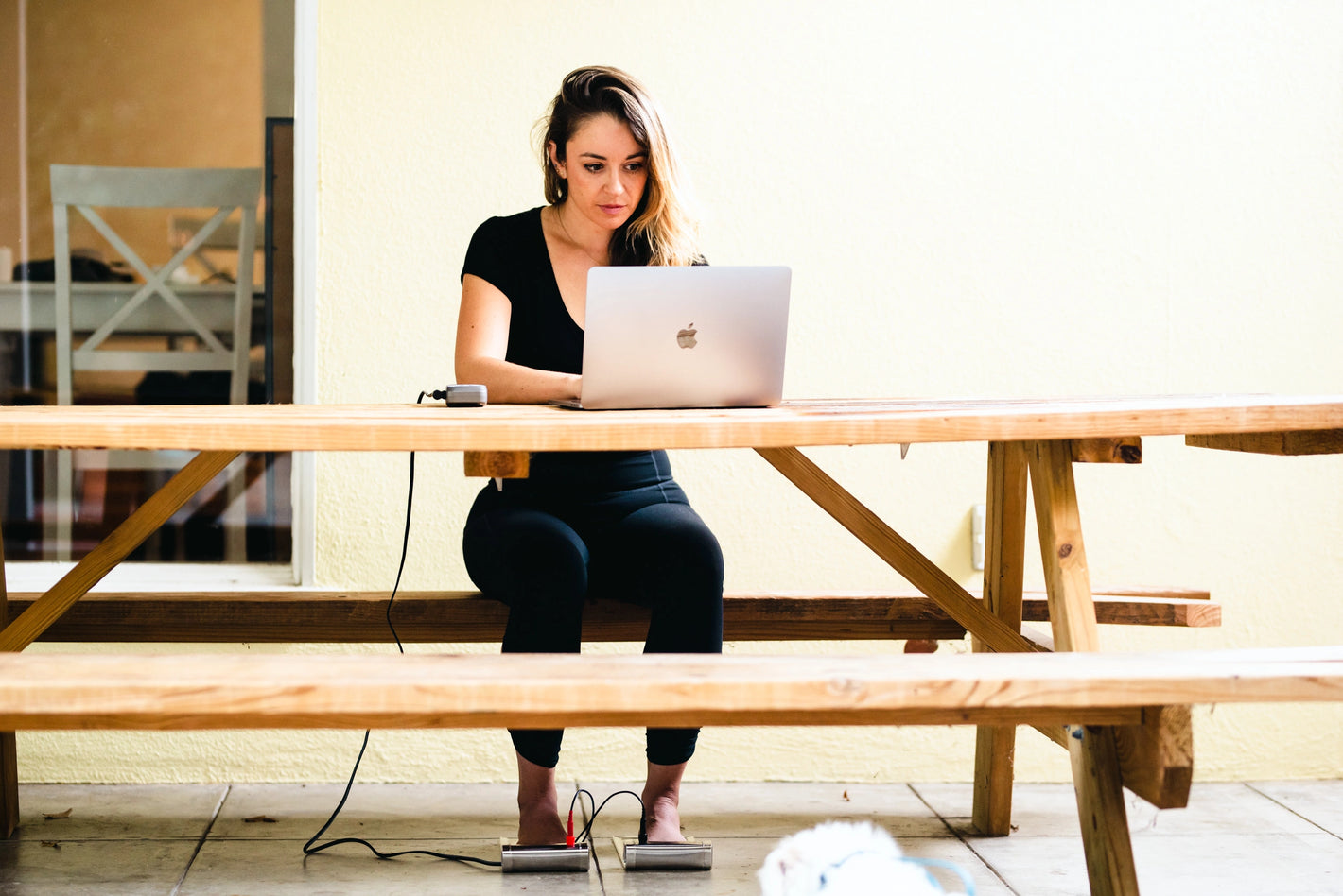 photo of a woman using the foot plates while working outside at a picnic table 